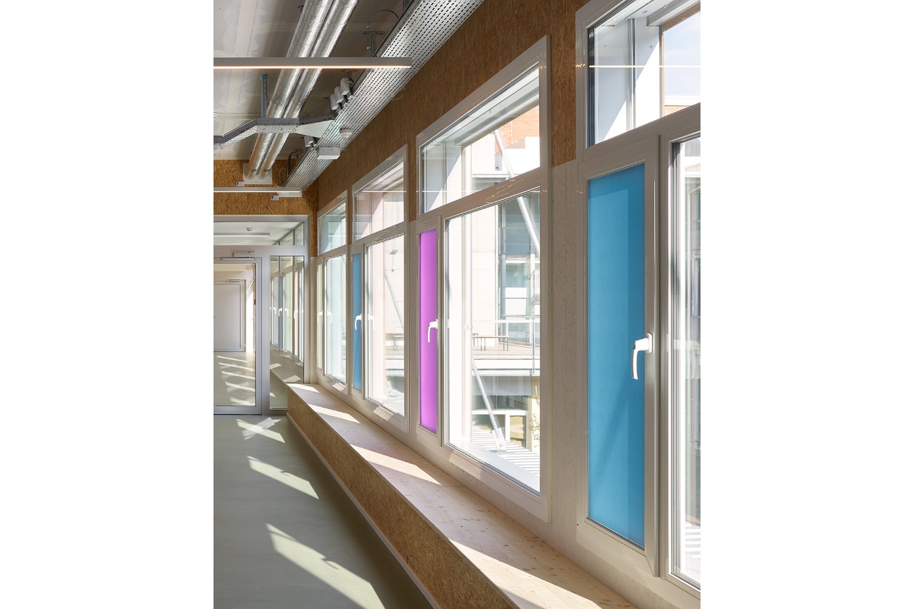 Der Erschliessungsgang vor dem Esssaal wird durch eine lange Holzbank und farbige Fenstergläser strukturiert (© Theodor Stalder, Zürich)
